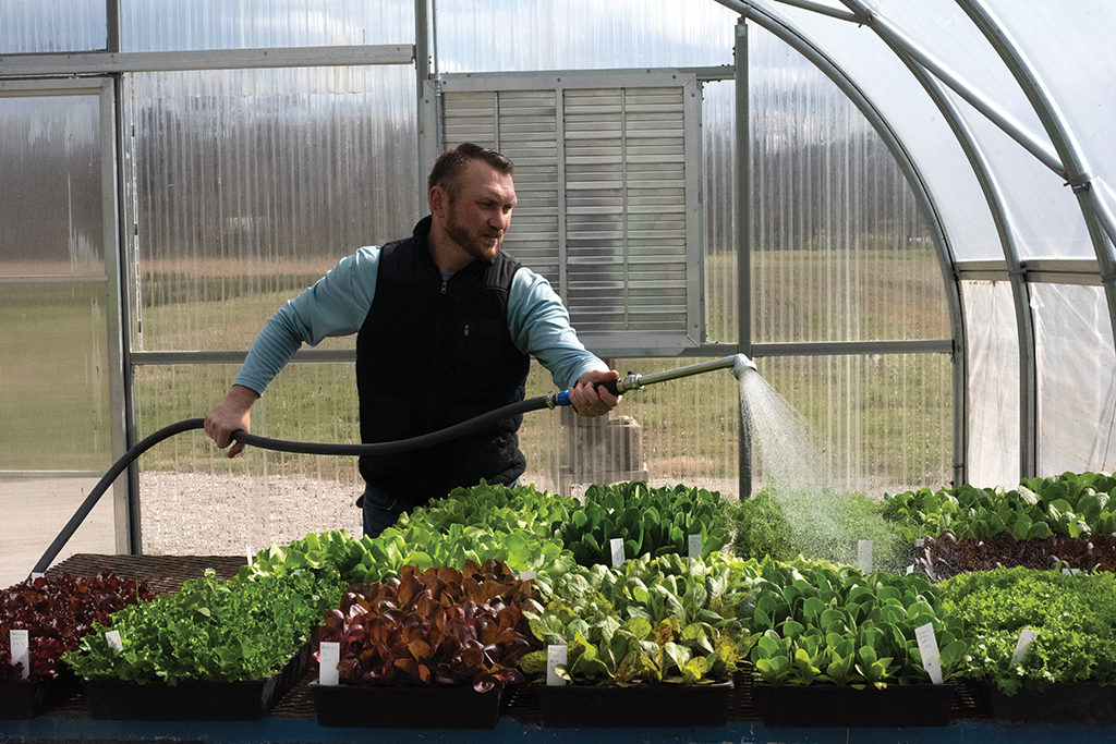 Kenny Holbrook waters plants in the greenhouse