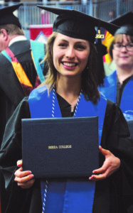A recent graduate proudly displays her diploma.