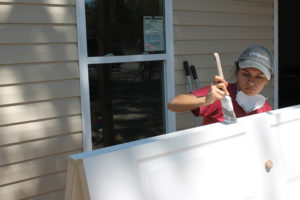A Berea College student painting a door for a home in Florida.