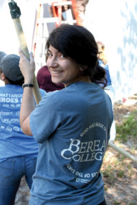 Mariah leads a group of students in painting a building site.