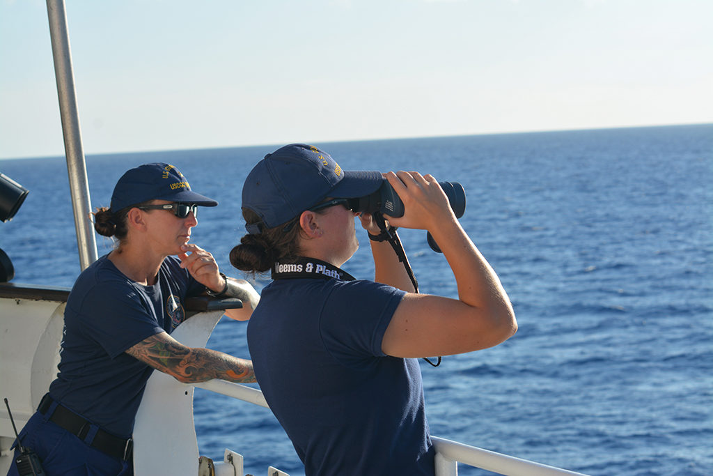 Two Coast Guard members on a ship in the ocean