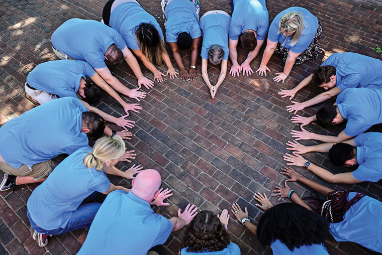 Members of the Campus Christian Center gather and bow down in the shape of a heart.