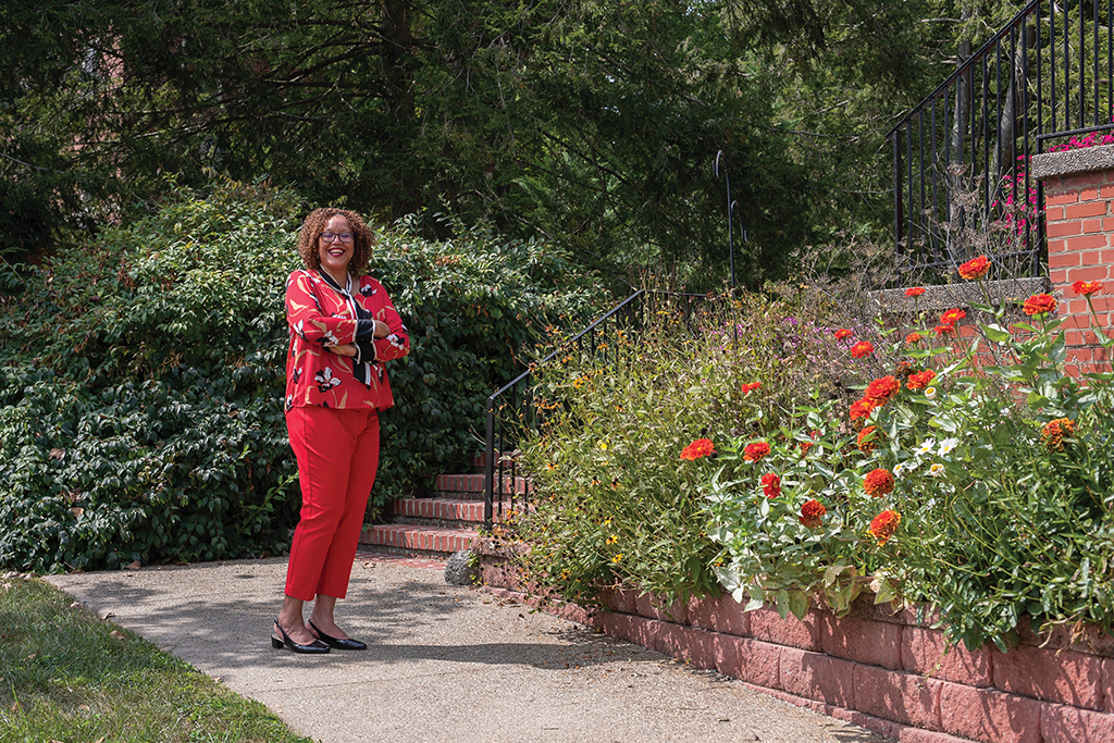 portrait of Channell Barbour standing in front of a staircase bordered by red flowers.