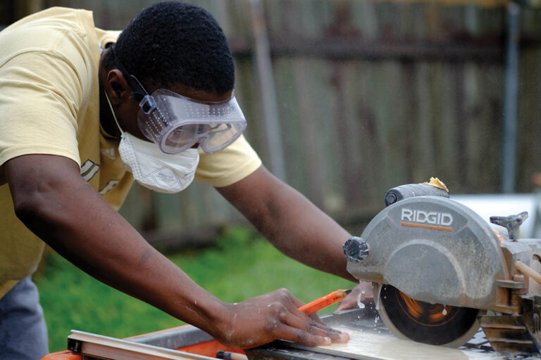 A Berea College student cutting tile with a table saw