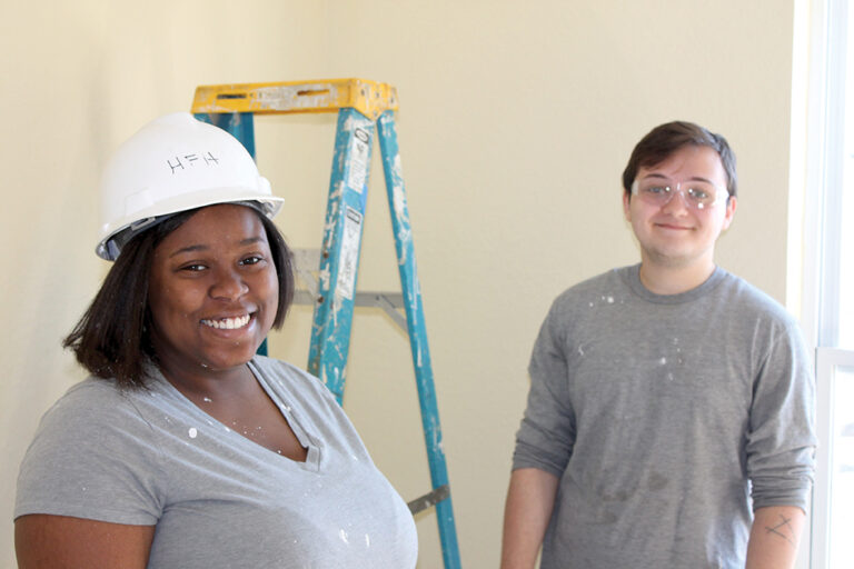 Two students work together to complete a project by Habitat for Humanity.