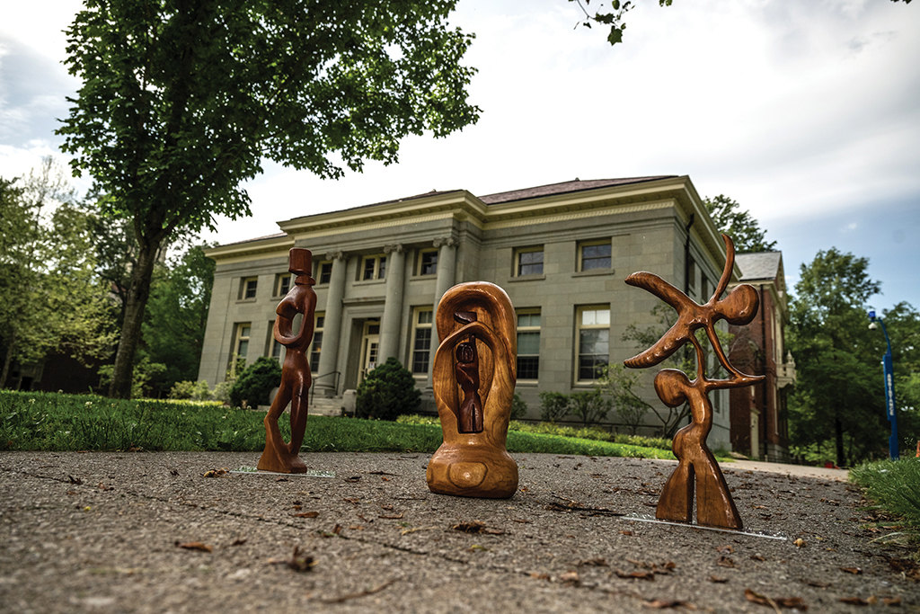 Three wooden figures carved by Tom Boyd, displayed in front of the Frost Building
