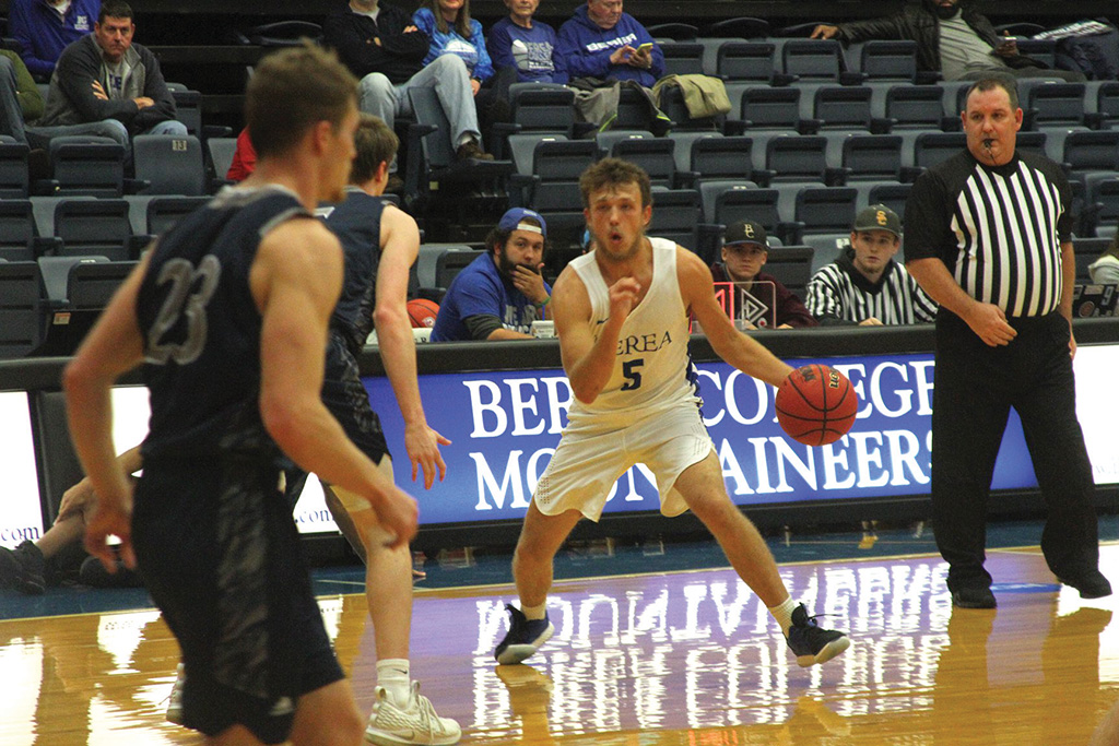 Isaac Caudill dribbles past a defender in a basketball game.