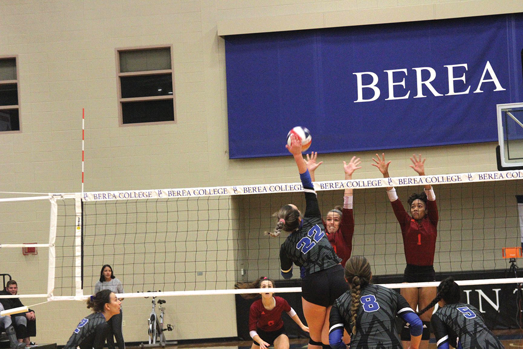 Vanessa Ramic spikes a volleyball over two Maryville College players.