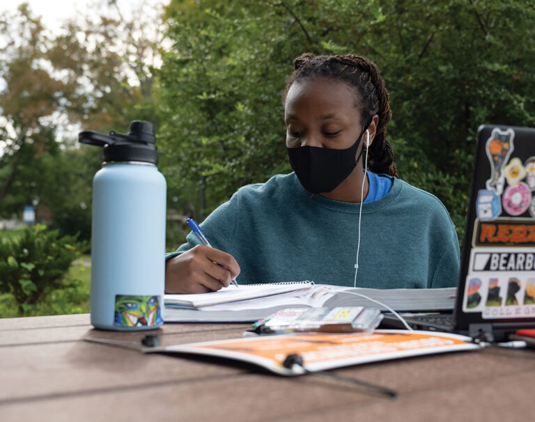 Student Kaela Davis ‘23 sitting at a table studying outside