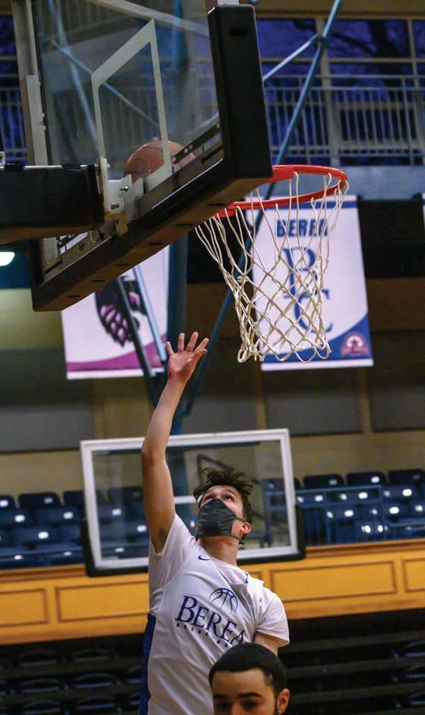 Men's basketball player shooting a layup while wearing a mask
