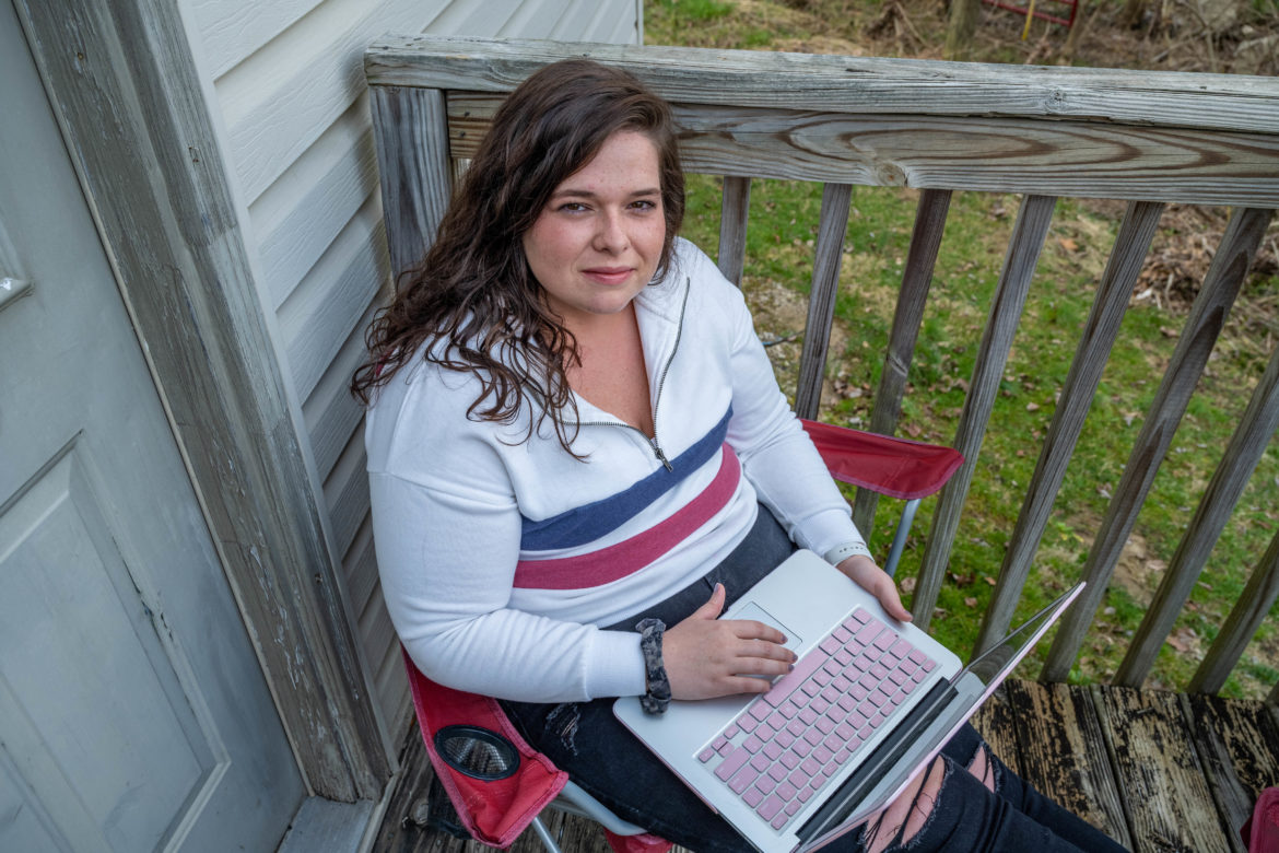 Inside and Outside of the Bubble Berea student sitting on a porch with a laptop