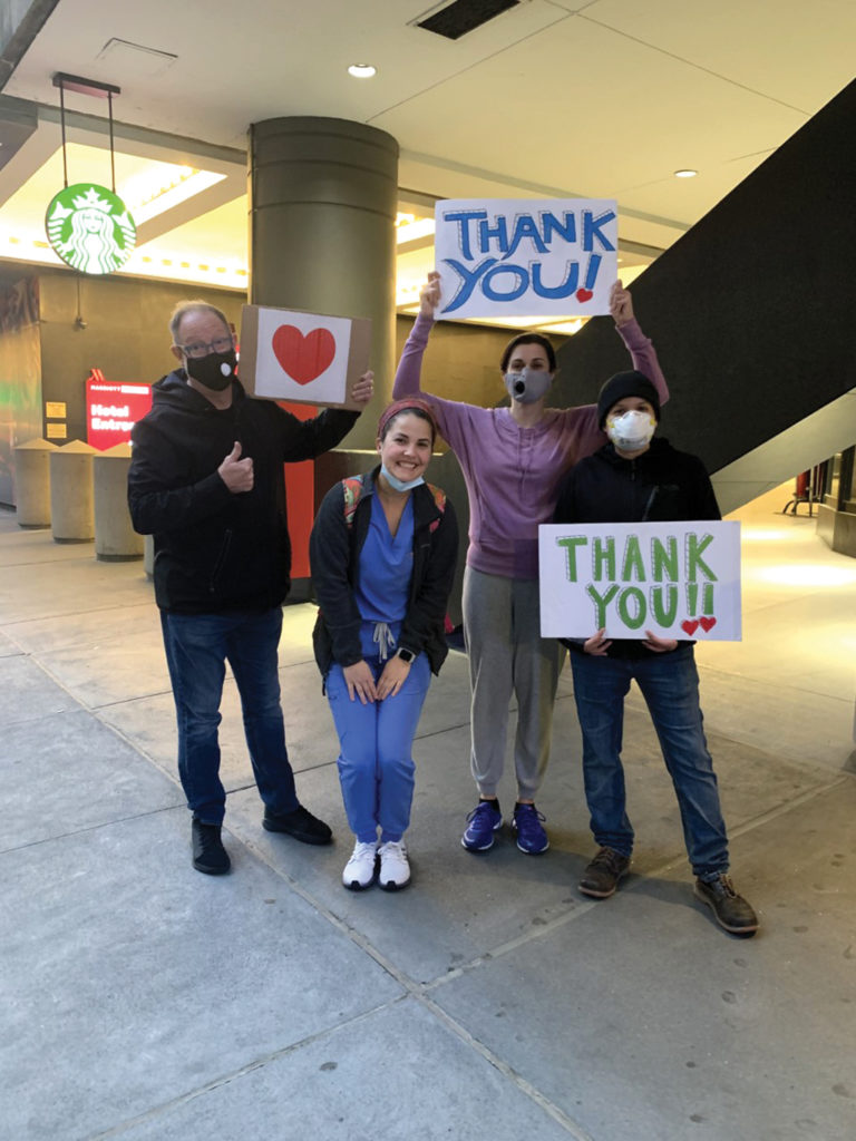 Trinity Goodman stands with people holding thank you signs in an airport