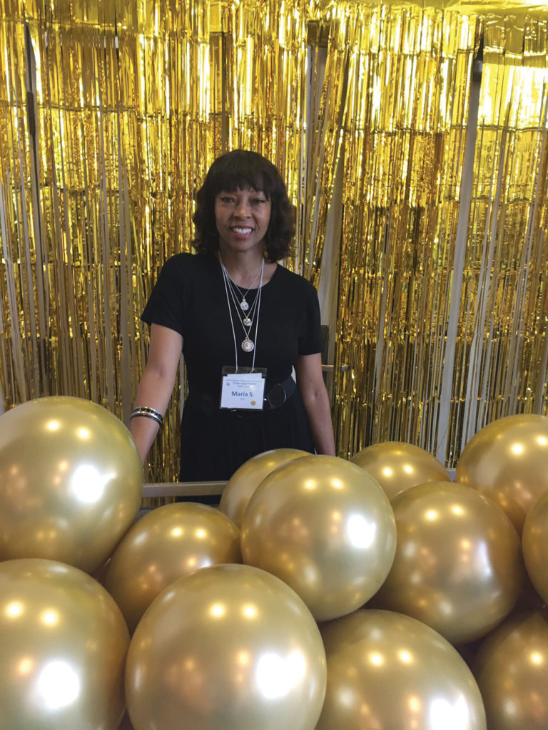 Photo of Maria Stephens surrounded by gold balloons