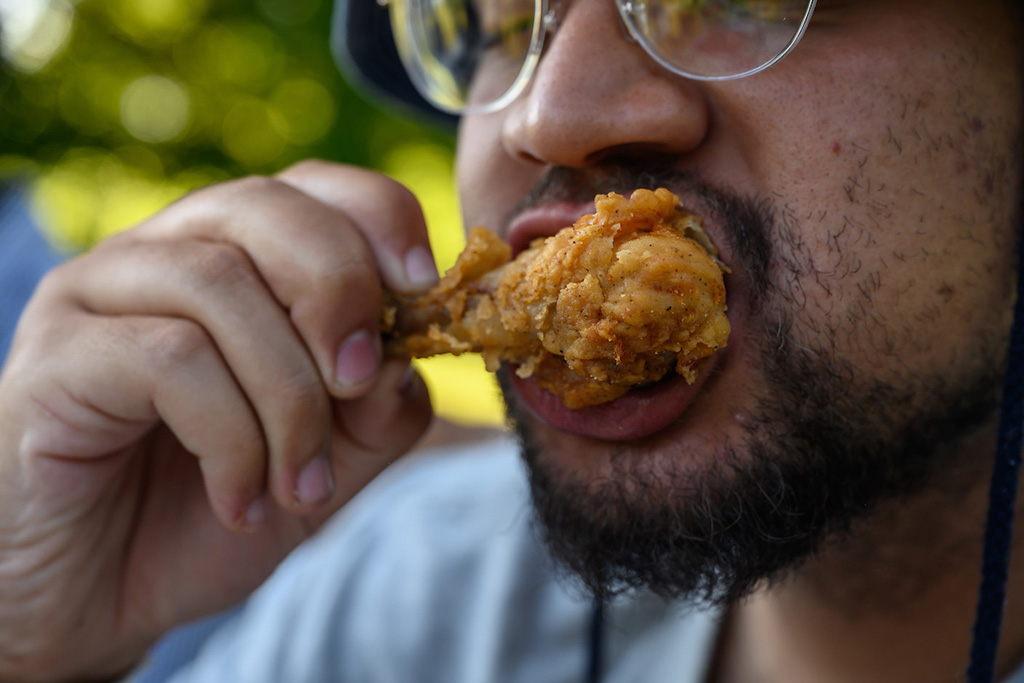Upclose photo of a man eating a chicken leg