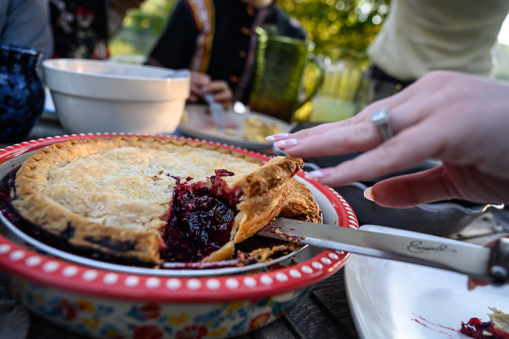A slice of triple berry pie being cut from a dish