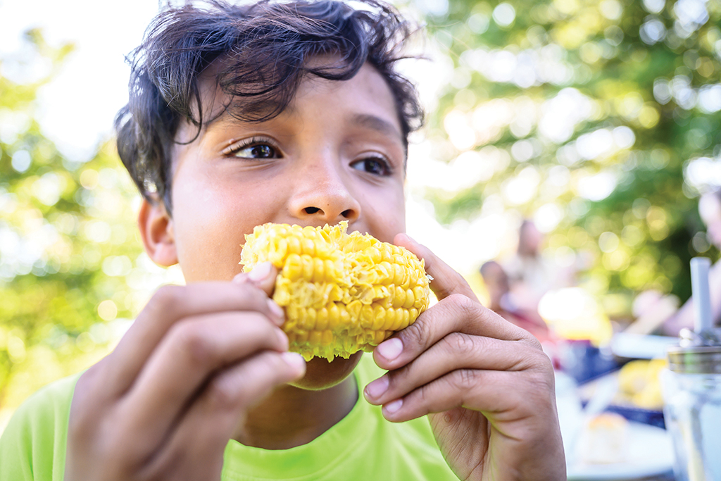 Up-close photo of a boy eating corn on the cob
