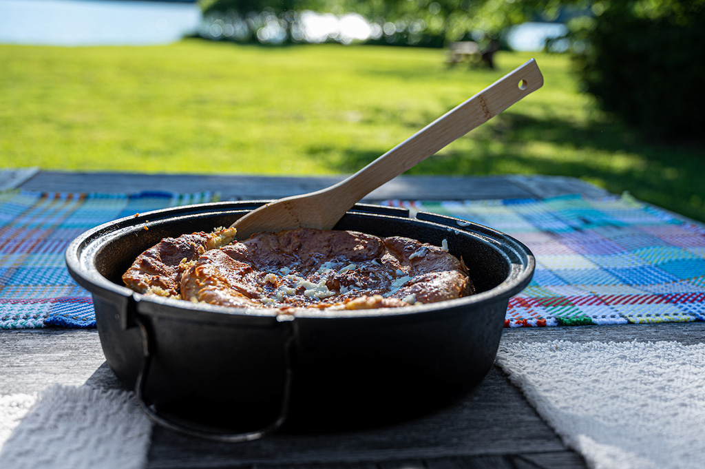 Cast iron skillet holding spoonbread sitting on a farm table next to Owsley Fork Reservoir