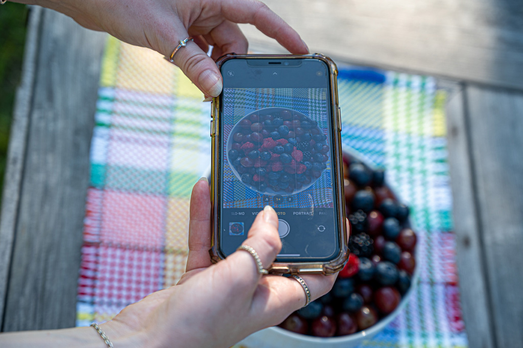 Photo of an iPhone taking a photo of a bowl of berries