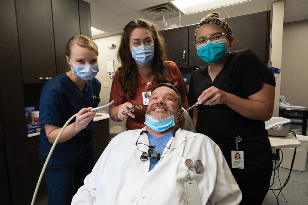 Three pre-dental students surrounding Dr. Dennis Canter