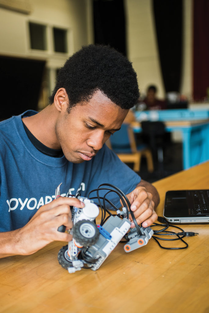 Male student piecing together a motorized piece of equipment