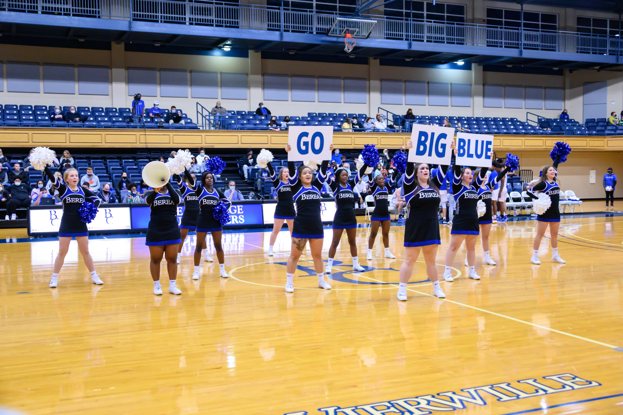 Cheerleaders hold signs on the basketball court