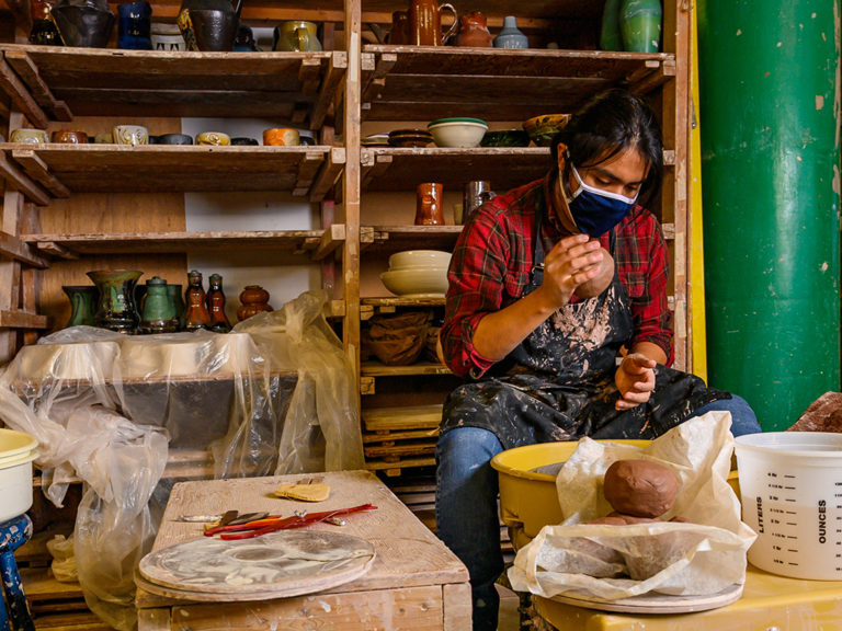 Photo of Jose preparing clay to throw a pot in the ceramics studio