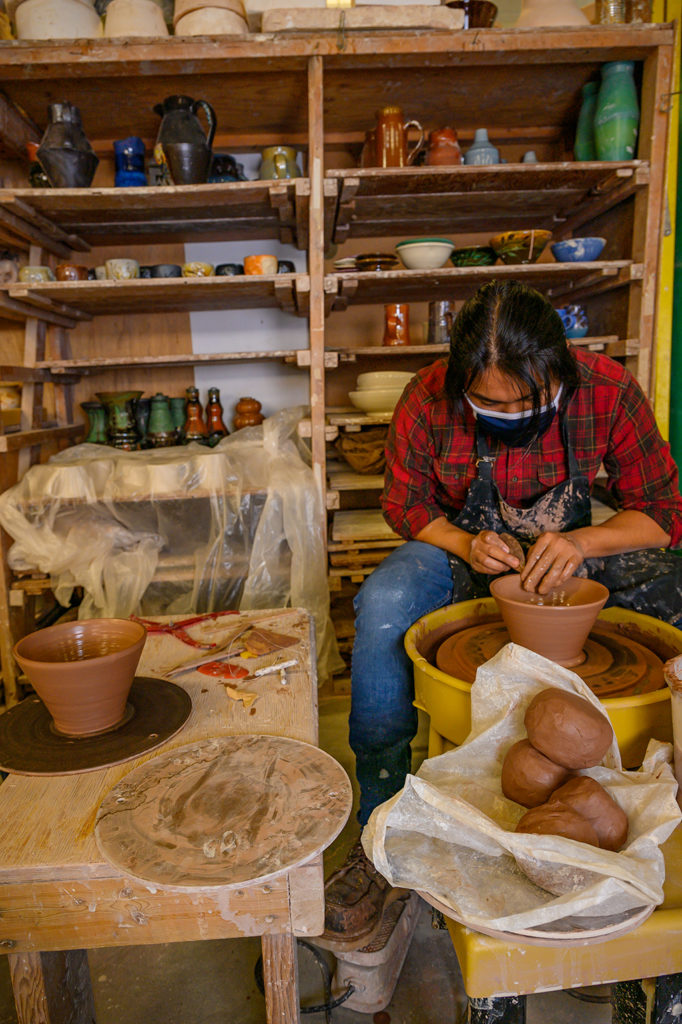 Photo of Jose smoothing a pot he is throwing on a pottery wheel