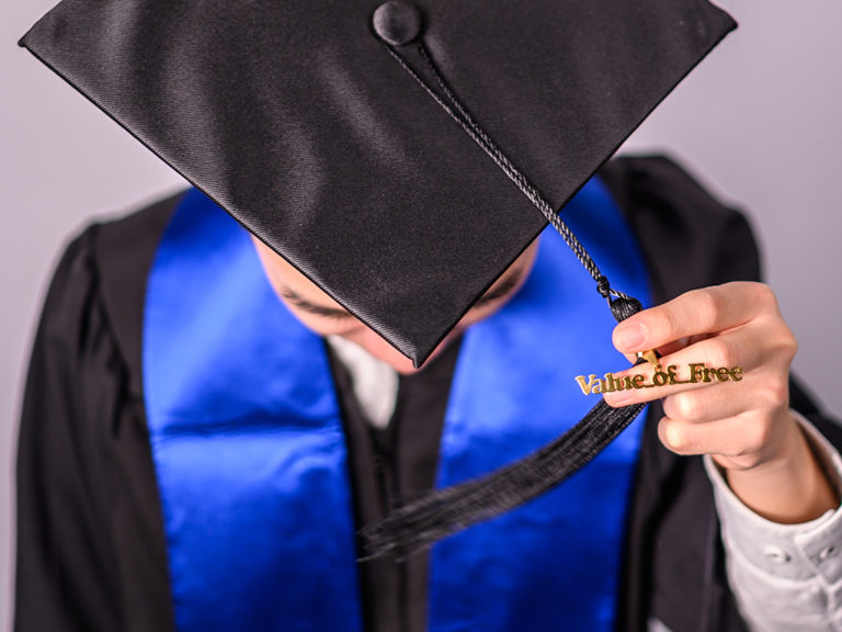 Student in graduation cap with an upclose of the tassle charm that reads Value of Free