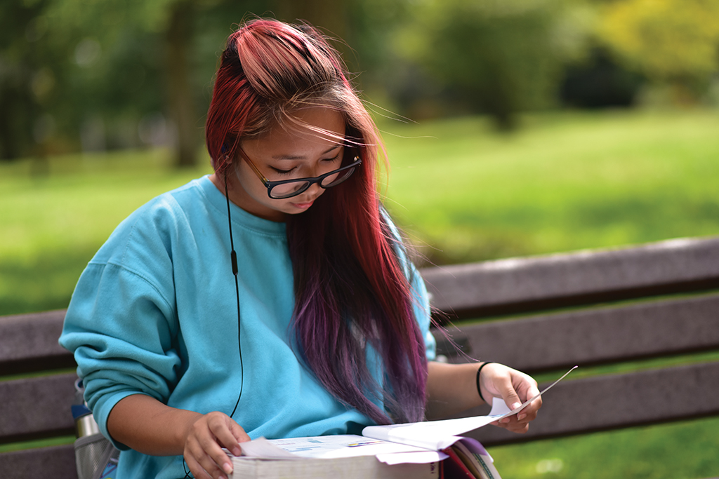 Image of a female student reading on a bench