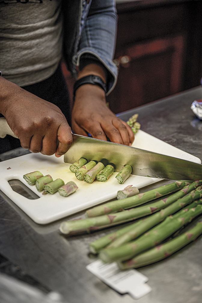 Photo of a student's hands chopping asparagus