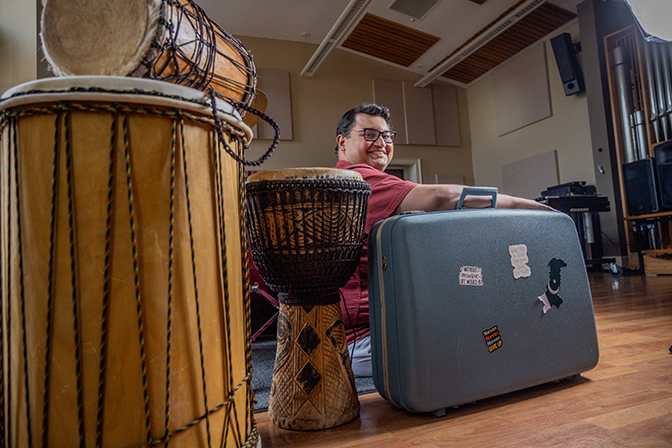 Portrait of Ali Hassan with percussion instruments and a suitcase