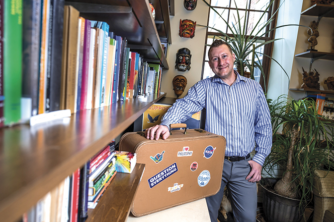 Portrait of Jarrod Brown in his office with a suitcase