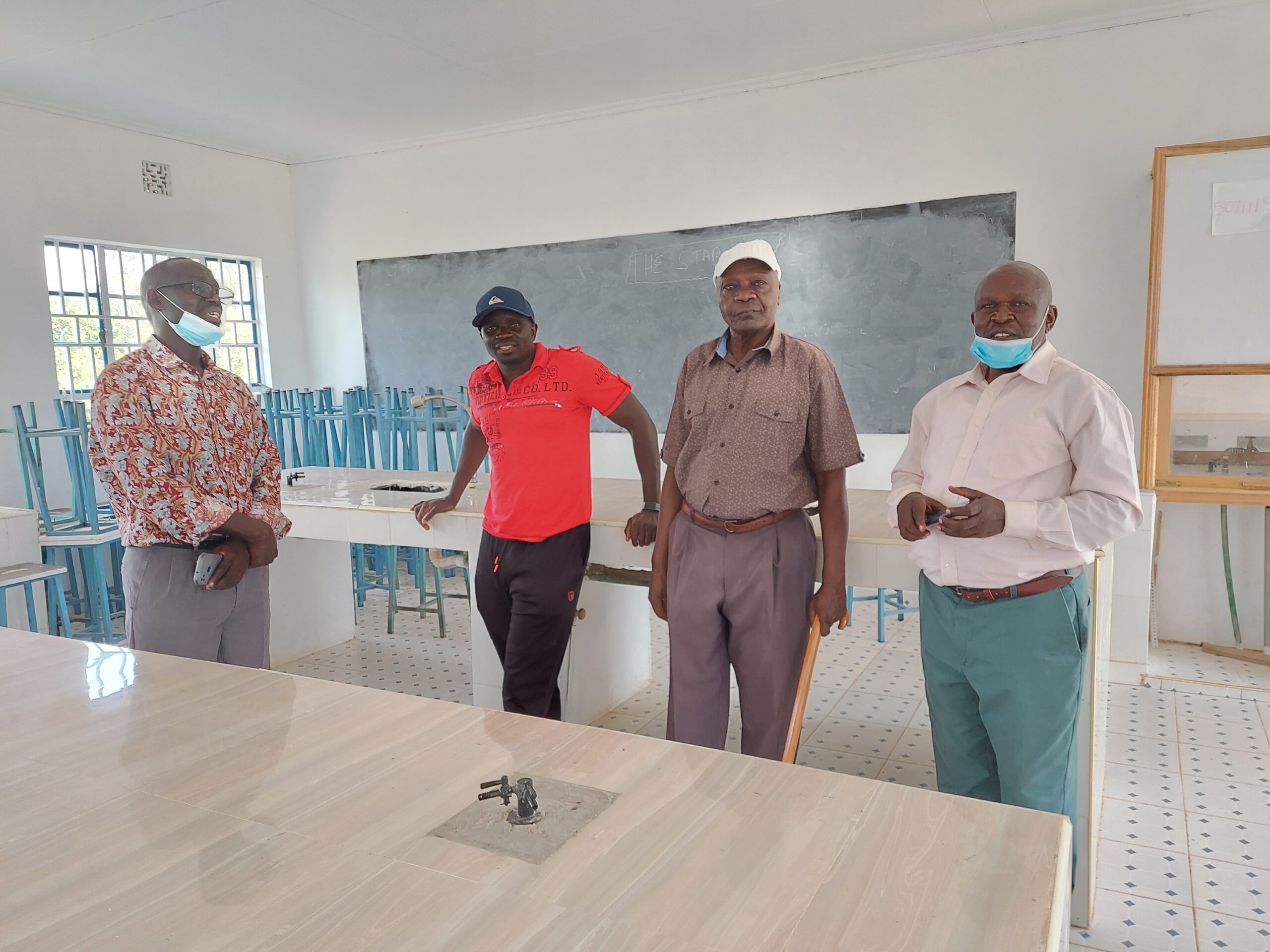 Four men standing in a classroom in Kenyan school