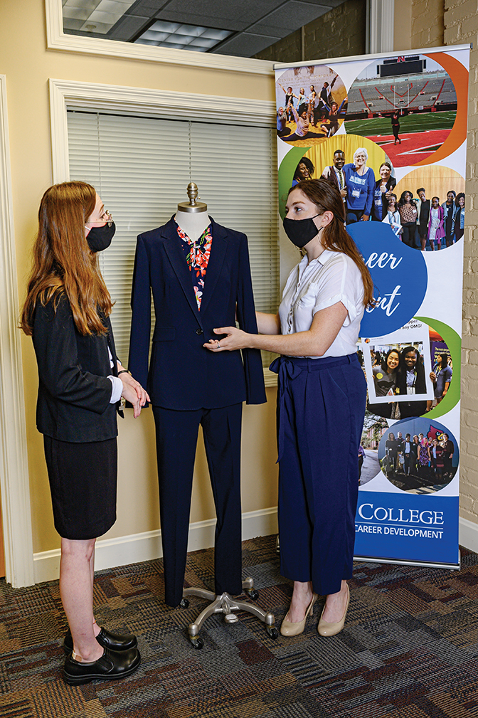 two students looking at a women's business suit in the Office of Internships and Career Development