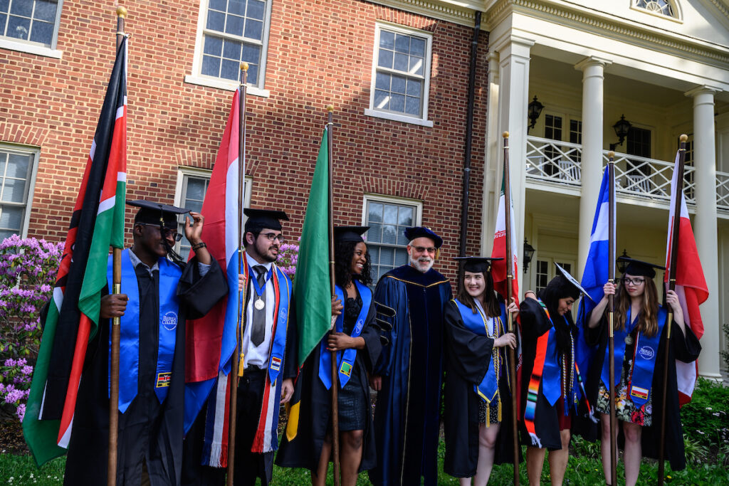 Dr. Richard Cahill with a group of international graduating students holding their countries' flags