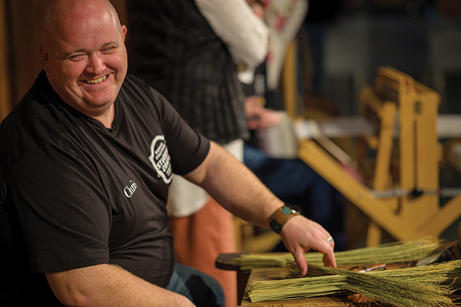 Broommaker Chris Robbis smiling at a broommaking demonstration.