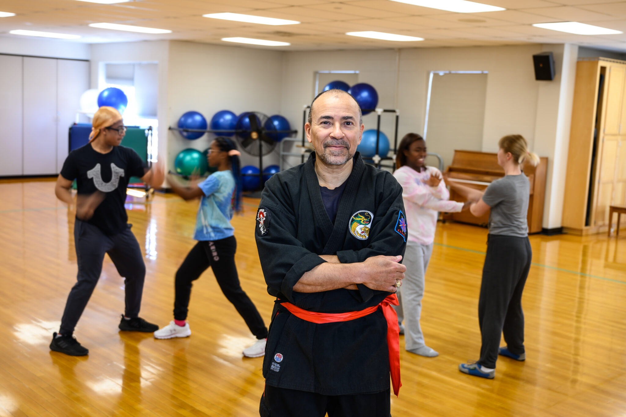 Dr. Jose Pimienta-Bey posing in front of his martial arts club in the dance studio of Seabury.