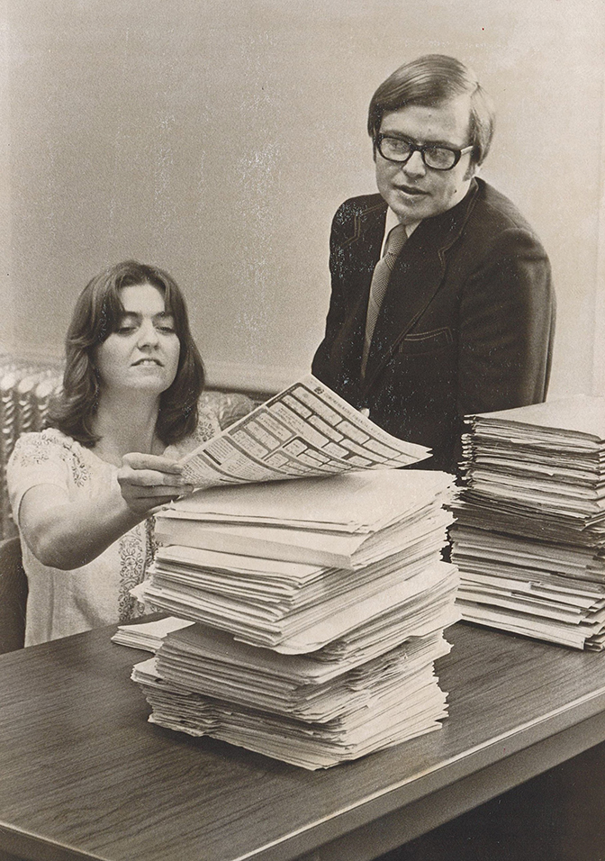 Black and white photo of Dean John Heniesen (right) working with a student filing papers.