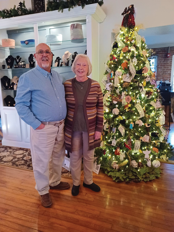 Portrait of Janet Ballengee Estep and her husband Larry Estep in front of a Christmas tree.