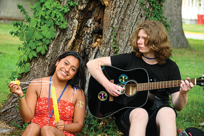 Two students haning out together, one holding a guitar