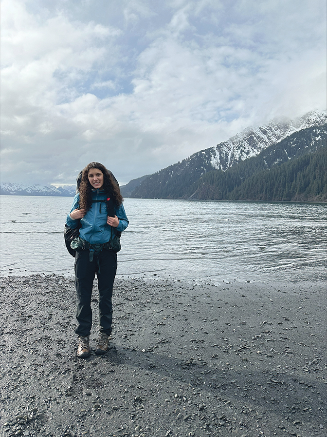 Alana '26 standing in Alaska with a snow-covered mountain behind her