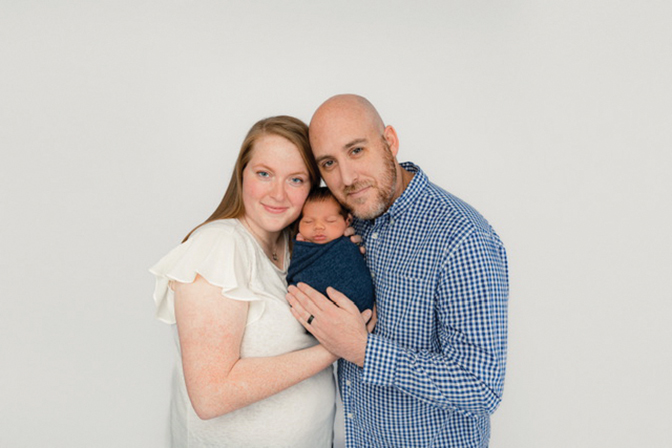 Portrait of Kimberly Osee Russel Collins with her husband and new baby.