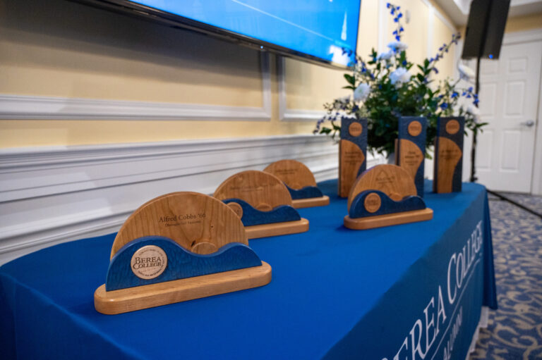 picture of all the alumni awards for 2024 at Homecoming sitting on a blue table cloth