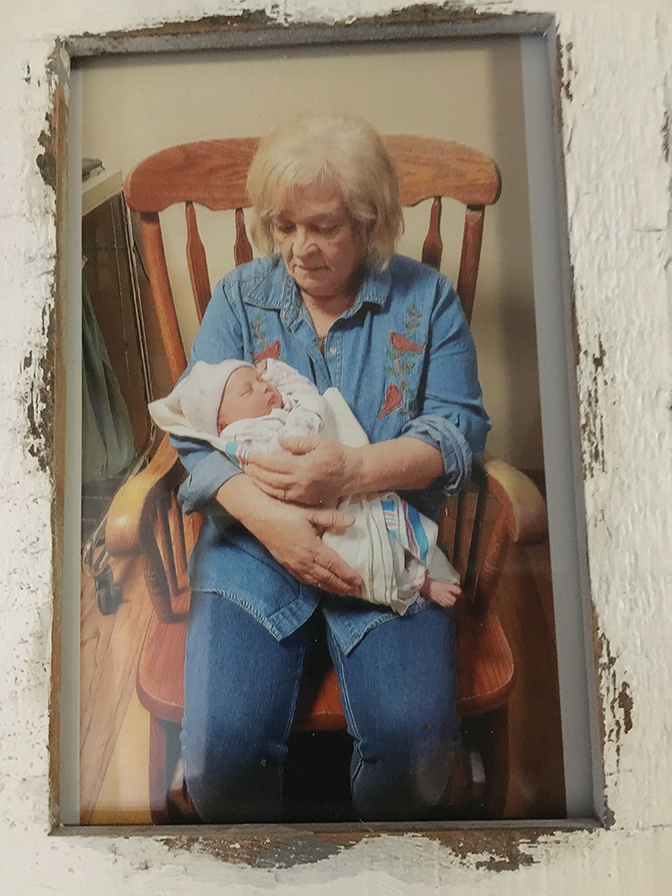 Photo of Kathy Johnston rocking a baby in an old fashioned rocking chair.