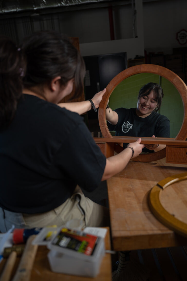 Student holds a wooden mirror and sees their reflection.