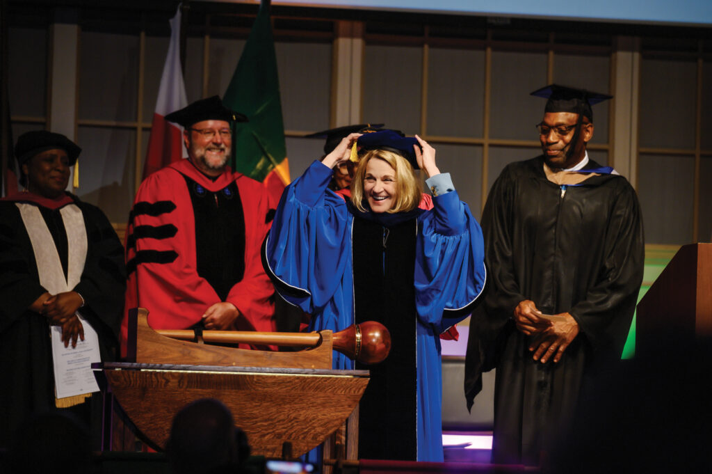 Dr. Cheryl Nixon placing her hat on her head after being robed as Berea's 10th president