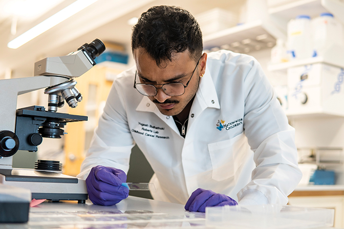 photo of Yogesh Budhathoki in a lab preparing a slide for a microscope.