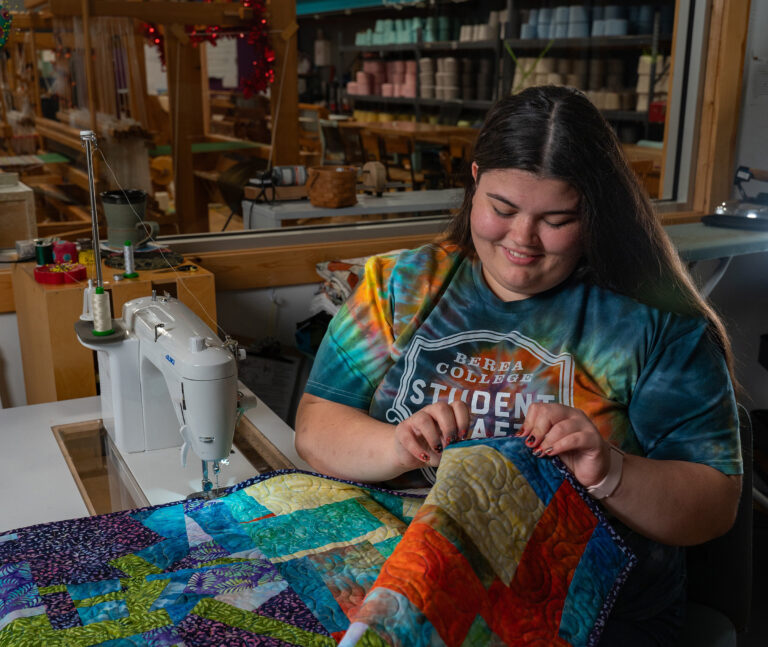 Photo of Dani Helton sewing a quilt in Student Craft