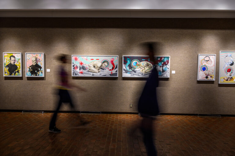 Blurred silhouettes walking past an art exhibit in one of the Doris Ulmann Galleries