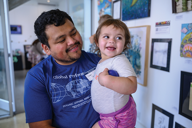 Alumnus holds smiling baby girl
